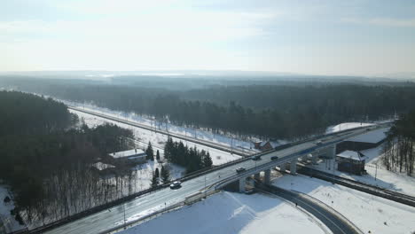 scenic aerial orbit shot of cars driving along snowy highway bridge in winter