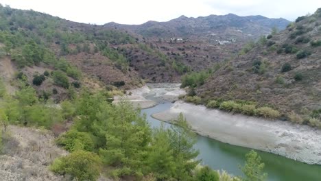 aerial view pulling back over the beautiful mountain valley at farmakas dam in cyprus