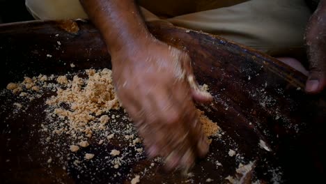 close up of man kneading flour dough in a wooden tray