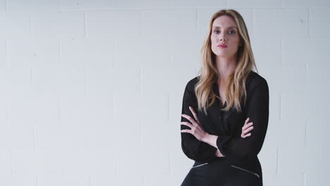 Fashion-Portrait-Of-Serious-Young-Woman-Standing-Against-White-Studio-Wall