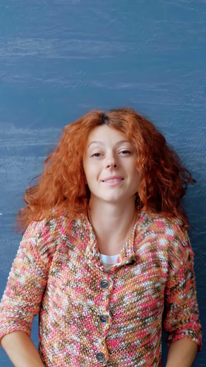 Woman with curly red hair is enjoying a moment of relaxation against a textured blue background, embodying a sense of peace and tranquility in her environment