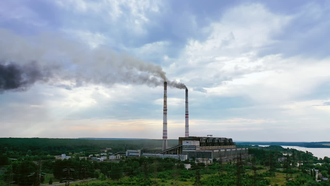 Industrial plant releases toxic emissions into the air. Smoke clubs come out of chimneys on a background of the sky. Nature in danger.