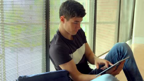 Happy-student-using-tablet-by-the-window