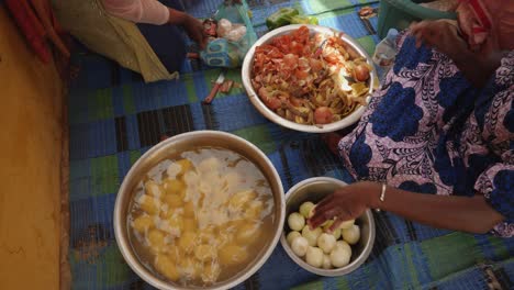 una toma desde arriba de una mujer africana preparando comida en el suelo