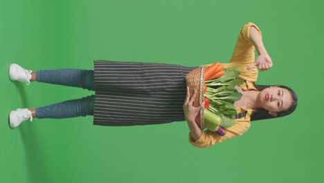 full body of asian female farmer with vegetable basket showing thumbs down gesture while standing in the green screen studio