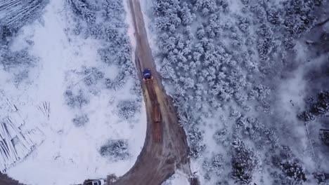 Un-Dron-Aéreo-Disparó-Un-Camión-De-18-Ruedas-Cargado-Con-Unidades-De-Madera-De-Pino-Maduras-En-Caminos-De-Tierra-En-Un-Campamento-Maderero-De-Invierno-Cubierto-De-Nieve,-Antes-Del-Amanecer-1