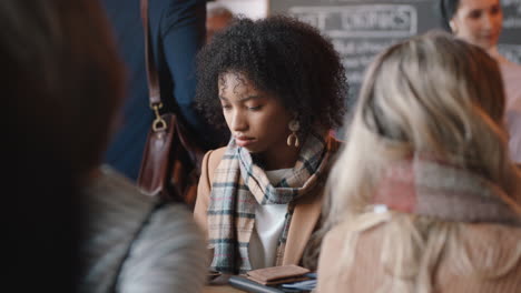 beautiful african american woman using smartphone in cafe texting sharing messages on social media enjoying mobile technology in busy restaurant