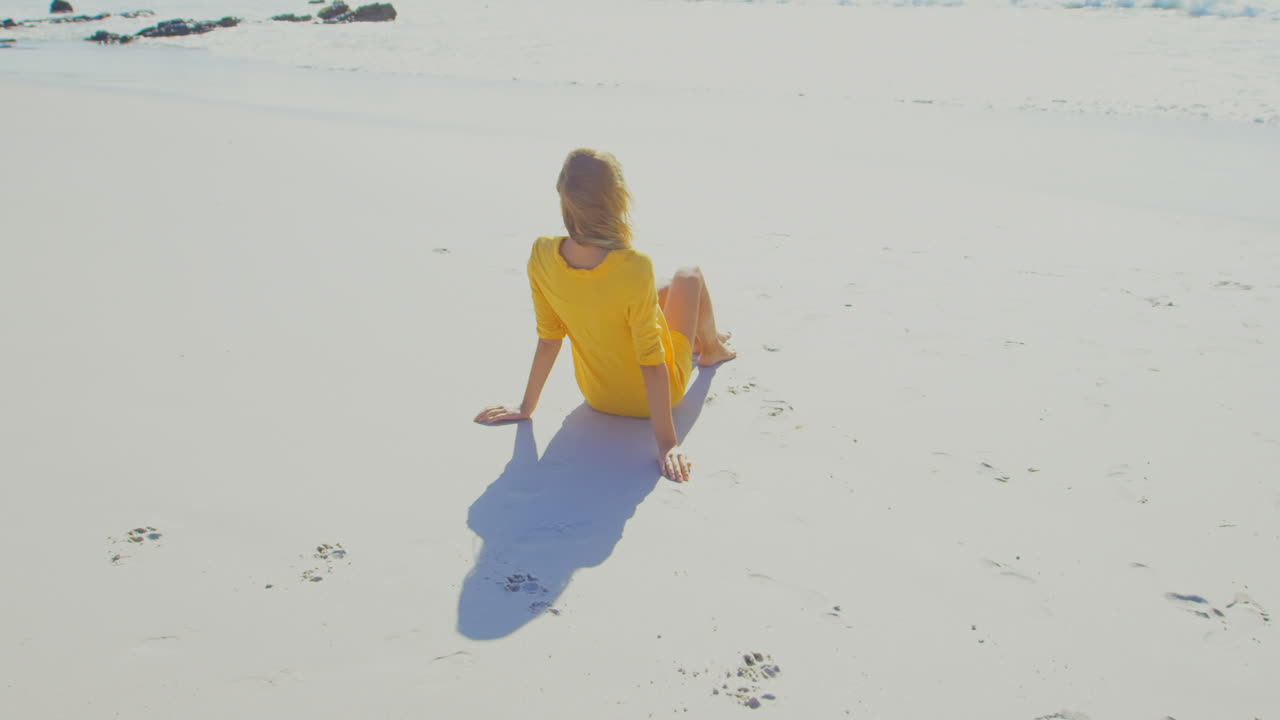 해변에서 휴식을 취하는 젊은 백인 여성의 뒷면 4k