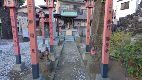 rolling shot of walking through torii gates towards small japanese shinto shrine in tokyo japan