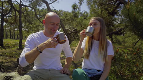 Couple-holding-mugs-and-hugging-in-forest