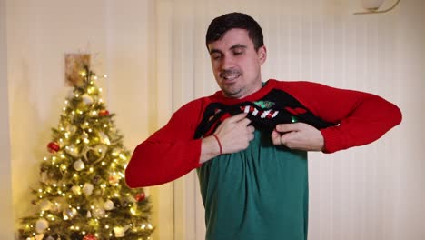 macho excitado poniéndose un puente navideño mirando a la cámara triste descubriendo que es del tamaño incorrecto, suéter corto a cámara lenta