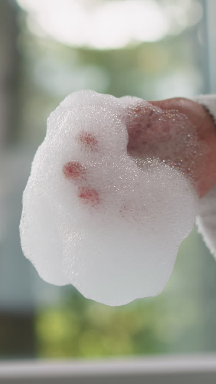 Woman gently touches soft bubble bath closeup. Lady in terry bathrobe holds foam cherishing calming aroma in morning. Body care procedures at home