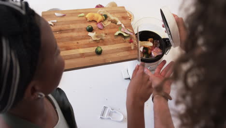 joven mujer afroamericana compostando residuos de alimentos en casa, con espacio para copiar