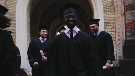 Group-of-multi-ethnical-happy-graduates-in-traditional-clothes-walking-through-the-University's-courtyard