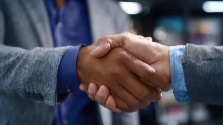 Un gesto di collaborazione: due persone che si stringono la mano saldamente, a simboleggiare la comprensione reciproca e la partnership in un ambiente professionale