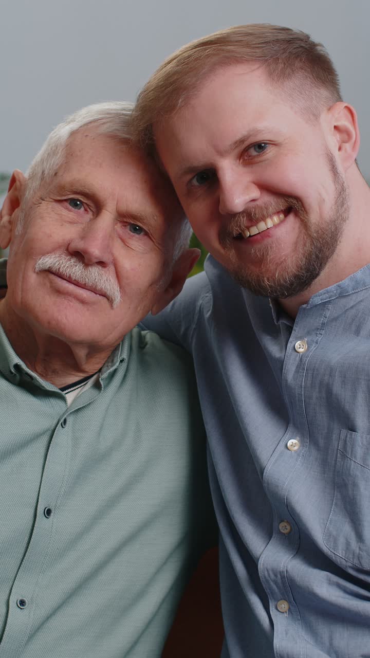 Retrato de avô sênior com neto jovem adulto sorrindo feliz abraçando abraçando em casa