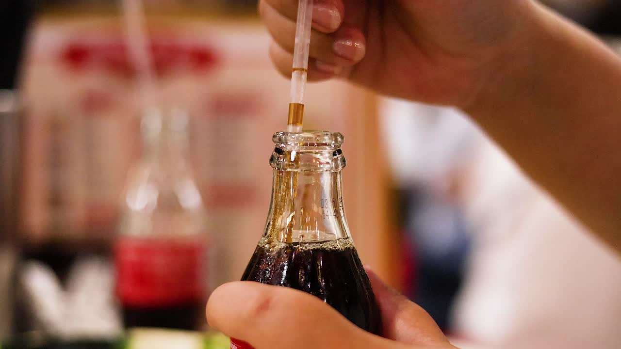 manos colocando paja en botella de refresco