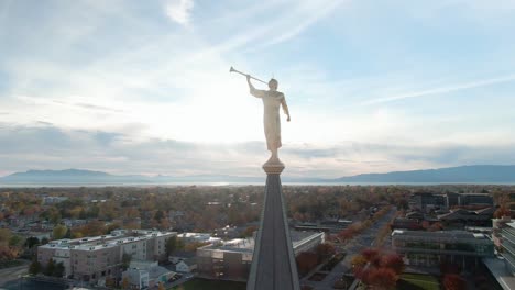 angel moroni statue with trumpet atop lds mormon temple at sunset in provo, utah - aerial orbit