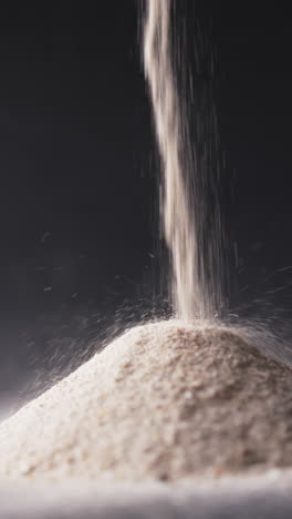 Vertical video of close up of heap of sand grains and copy space on black background