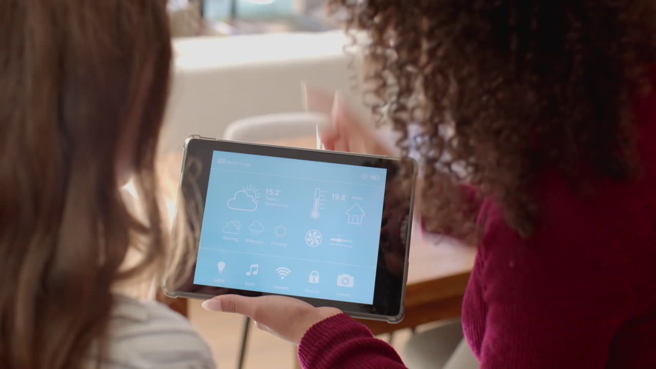 Using tablet, lesbian couple managing smart home system together in living room