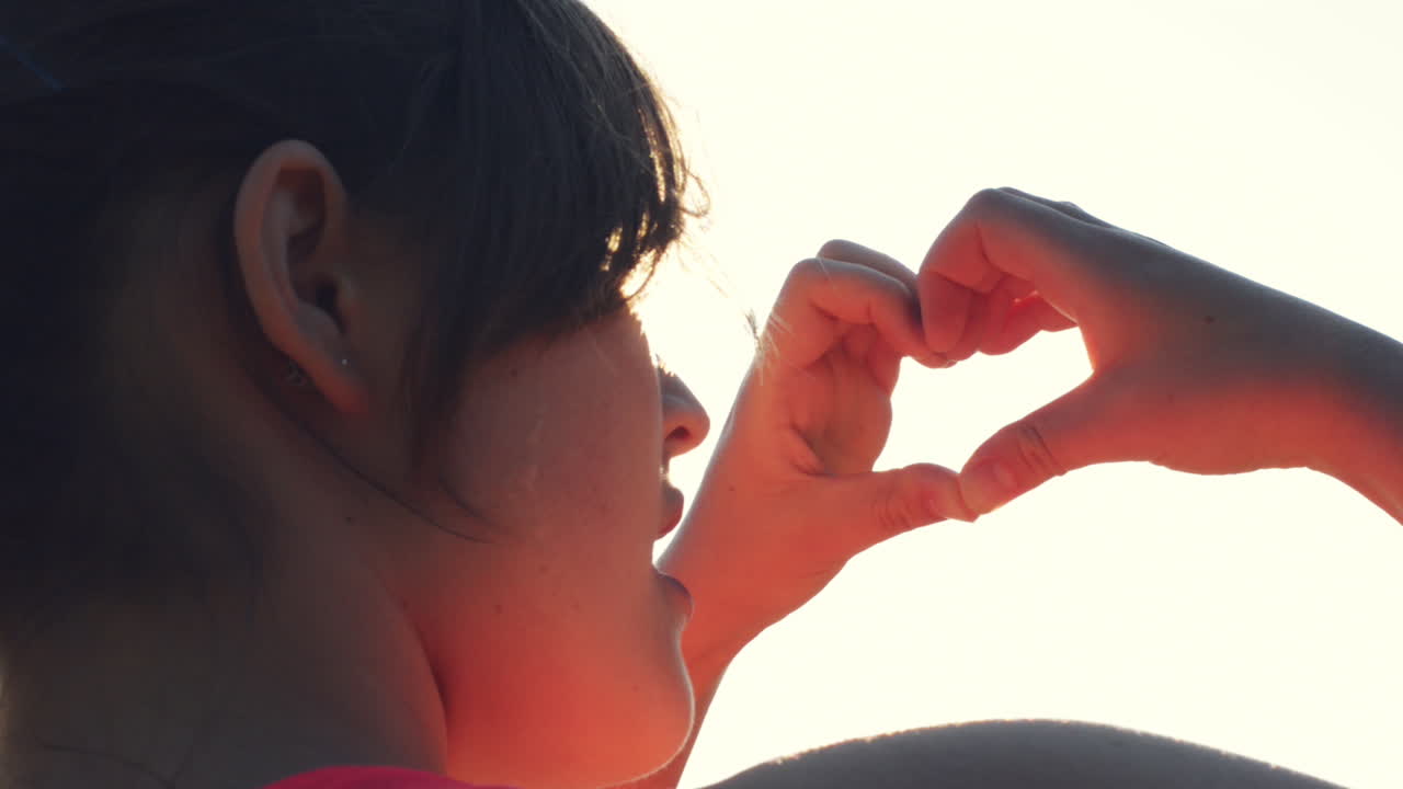 여성의 손은 심장 모양의 몸짓으로  ⁇ 빛을 들고 있습니다.