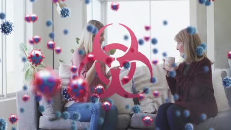 animación de células de virus y símbolo de peligro biológico sobre amigas caucásicas sentadas en el sofá