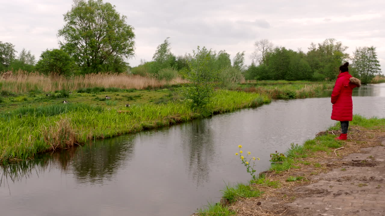 En indisk kvindelig fuglekigger står nær en kanal i Giethoorn, Holland.
