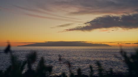 Sun-setting-down-behind-silhouette-of-lonely-island,-time-lapse-view