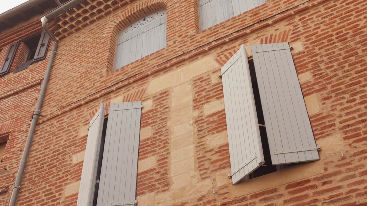 Historic brick building in Albi with shutters, evoking charm