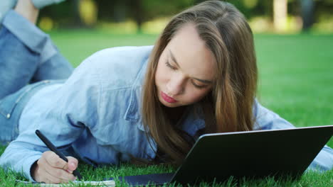 Estudiante-Mujer-Escribiendo-En-Un-Cuaderno-Desde-Una-Computadora-Portátil-En-El-Campus-Universitario