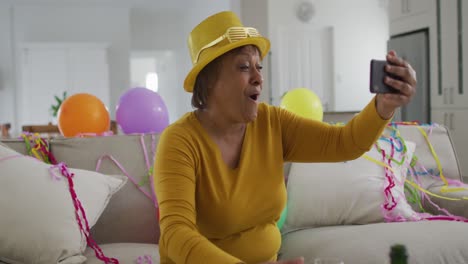 Happy-african-american-senior-woman-holding-champagne-making-new-year's-eve-smartphone-video-call