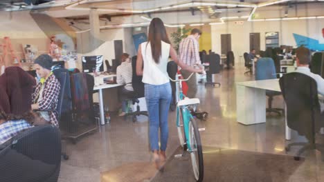 Animation-of-hands-using-laptop,-over-colleagues-at-creative-office-with-bike-and-on-hoverboard