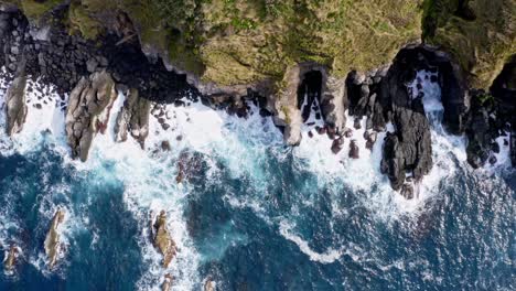 foamy waves washing rugged rocky coastal cliffs of azores, overhead