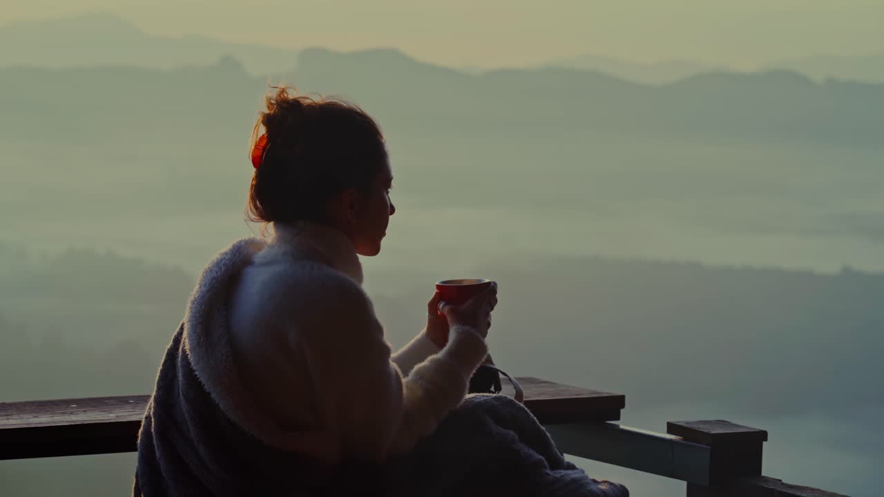 Femme savourant une boisson chaude avec une vue sur des montagnes brumeuses