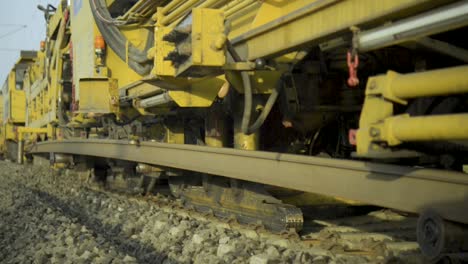 Close-up-of-yellow-railroad-machinery-on-tracks-during-the-day,-focusing-on-technical-components