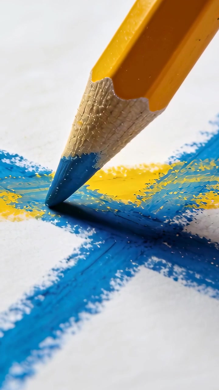 Video verticale: Matita con anima giallo-blu che tocca e aggiunge pigmento blu su una croce sulla carta, intensificando