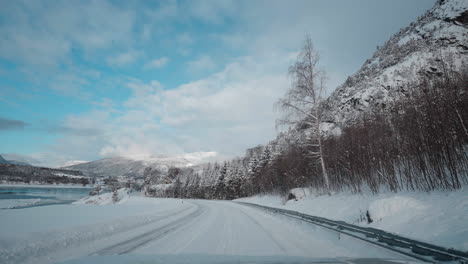 pov footage of a winter drive, showcasing snowy mountain roads and the stunning view of fjords under a clear blue sky