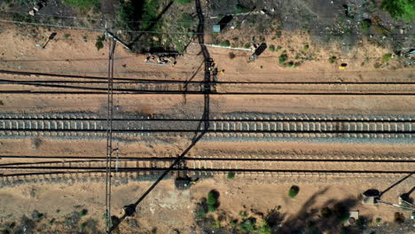 Aerial-drone-top-shot-following-an-abandoned-railway-train-track-in-an-arid-desert-sand-environment