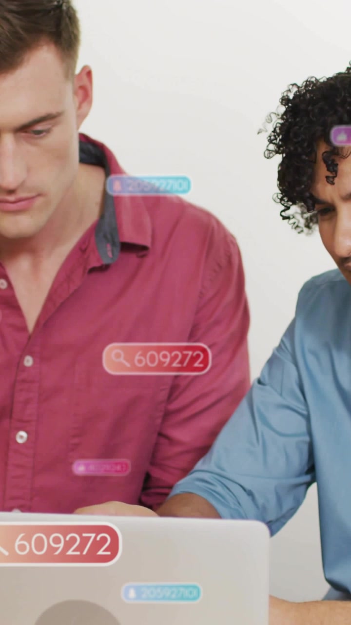 Two men leaning over laptop in tech demo, cursor clicking badge 609272 revealing results for review