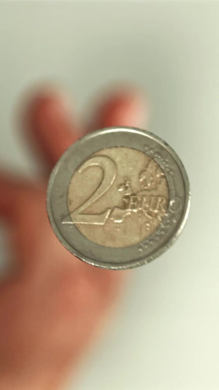 Primo piano in movimento rallentato di una moneta da due euro che volteggia in aria