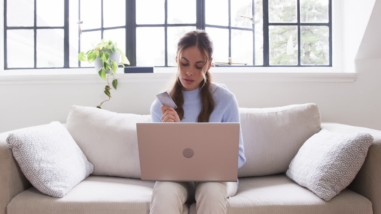 At home, woman shopping online with laptop and credit card, looking focused