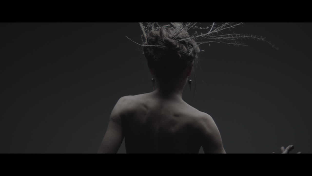 A woman dressed as mother nature moves slowly in a dance-like motion