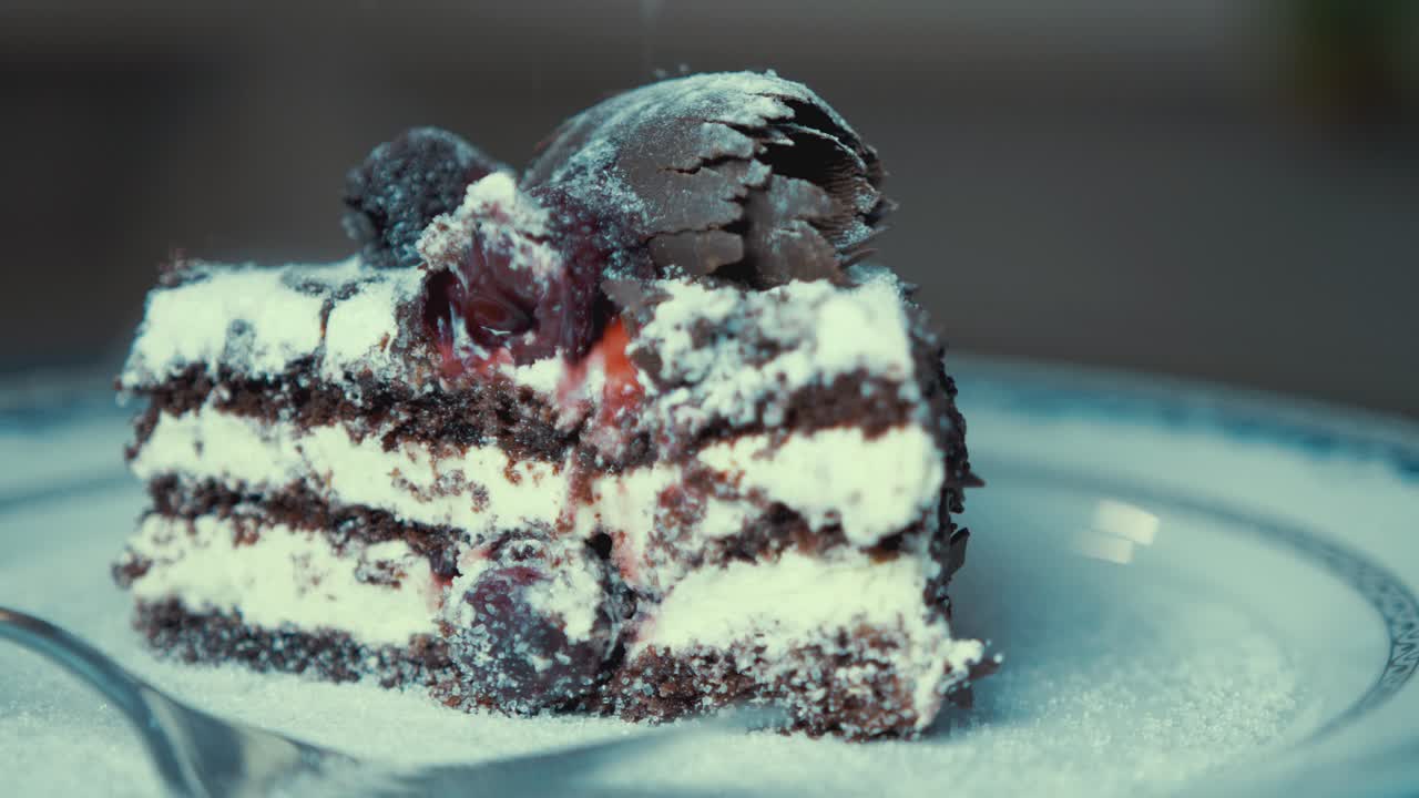 Chocolate cream cake topped with glazed cherries appetizingly spinning on plate