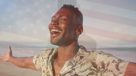 animation of flag of united states of america over happy african american man on beach