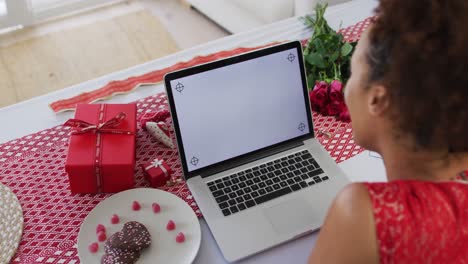 Mixed-race-woman-on-a-valentines-date-video-call-using-laptop-computer