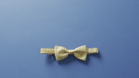 Video-of-yellow-dotted-bow-tie-lying-on-blue-background