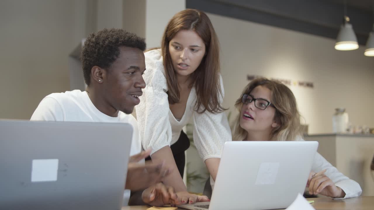 Creative team sitting and standing at table with laptops