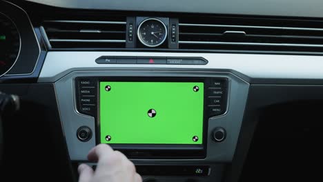 close-up of young man using navigation app on mounted mock-up greenscreen inside modern car. man driving car in the street with mobile navigation on greenscreen smartphone attached on dashboard