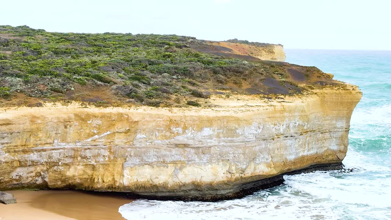 Aerial view of rugged cliffs and crashing waves at Port Campbell, Australia. Bright daylight enhances the natural beauty and vibrant colors