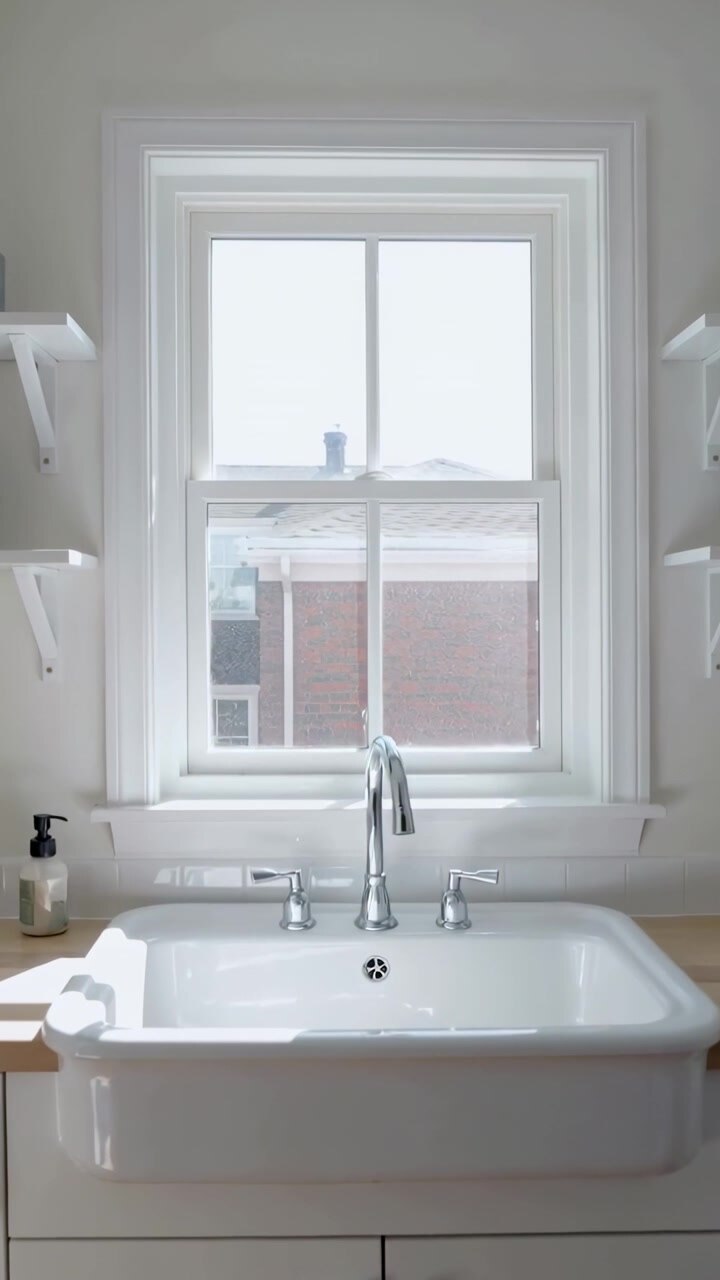 Vertical video: Camera settling upward, revealing sink basin with chrome faucet at kitchen window